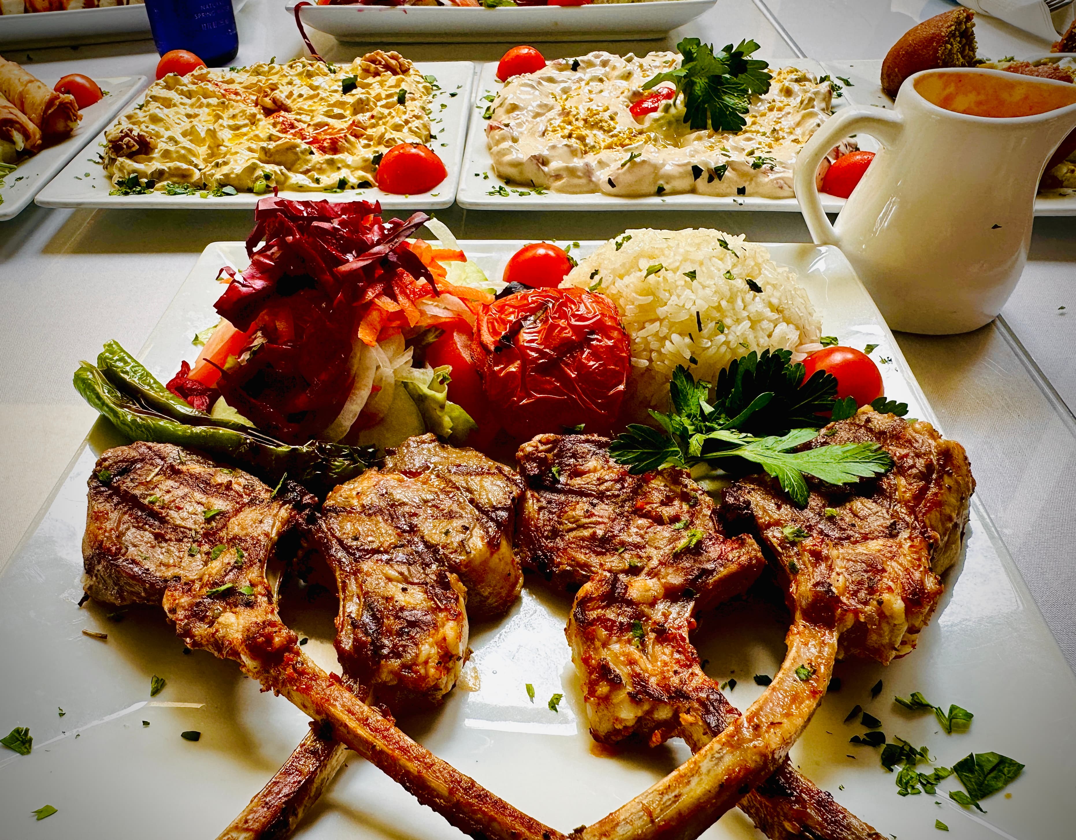 Charred baby lamb chops, crossed and plated with rice, grilled tomato and salad at Bodrum Restaurant